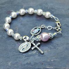 Celebrate the Baptism of a baby girl with this beautiful white and rosaline pink guardian angel rosary bracelet. The bracelet features genuine Swarovski crystals and crystal pearls throughout. The bracelet has white Swarovski pearls for the Hail Mary prayers and just a touch of rosaline pink with the larger Our Father pearl. In between are sparkly Swarovski crystals with an aurora borealis finish. The Our Father pearl is surrounded by crystal rhinestone rondelles. If you select the personalizati Personalized Pink Spiritual Bracelets, Personalized Pink Spiritual Bracelet, Spiritual Personalized Pink Bracelets, Spiritual Personalized Pink Bracelet, Spiritual Pink Personalized Bracelets, Spiritual Pink Jewelry For Birthday, Adjustable Pink Jewelry For Baptism, Personalized Pink Charm Bracelet For Wedding, Personalized Pink Spiritual Charm Bracelet