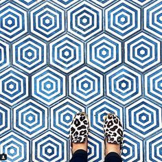 a person wearing leopard print shoes standing in front of a blue hexagonal pattern