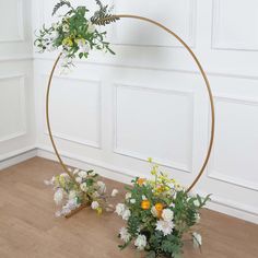 two vases filled with flowers sitting on top of a wooden floor next to a white wall