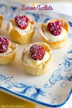 small pastries with raspberries are on a blue and white plate