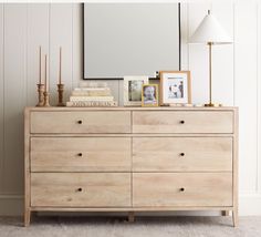 a wooden dresser with pictures and candles on top