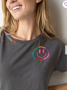 a woman wearing a t - shirt with a smiley face drawn on it