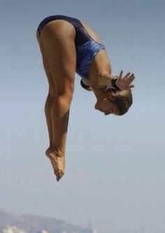 a woman diving into the water with her hands in the air while wearing a blue swimsuit