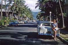 a woman is sitting on the back of an old car in front of palm trees