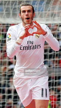 a soccer player is making a heart shape with his hands as he stands in front of the net