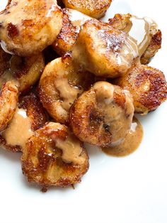 fried bananas covered in caramel sauce on a white plate