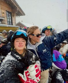 two women standing next to each other in front of a building with snow falling on them