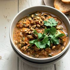 a white bowl filled with beans and cilantro on top of a wooden table