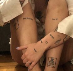 two people with matching tattoos sitting on the floor next to each other and holding hands