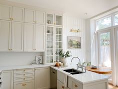 a kitchen with white cabinets and an island in front of a window that looks out onto the yard