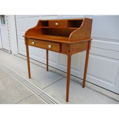 a wooden desk sitting in front of a garage door with a grate underneath it