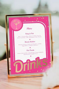 a pink menu sitting on top of a wooden table next to a white flower vase