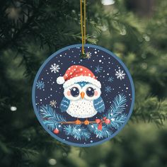 an ornament hanging from a christmas tree decorated with an owl and snowflakes