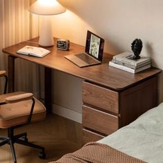 a laptop computer sitting on top of a wooden desk next to a lamp and chair