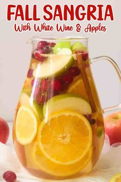 fall sangria with white wine, lime and apples in a glass pitcher on a table