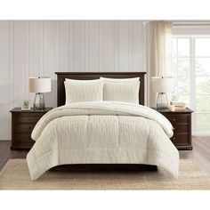 a bed with white comforter and pillows in a room