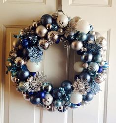 a christmas wreath hanging on the door with ornaments around it and snowflakes