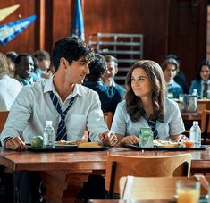 a man and woman sitting at a table in front of a group of people eating food