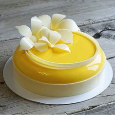 there is a yellow cake with white flowers on the top and bottom, sitting on a wooden table