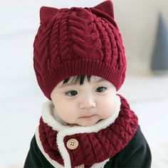 a small child wearing a red knitted hat and scarf with a cat ear flap