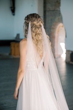 the back of a bride's dress as she walks down the aisle with her veil draped over her head