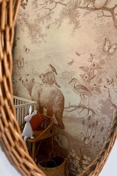 an animal themed wallpaper in a baby's room with a basket on the floor