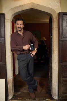 a man standing in an open doorway holding a coffee mug