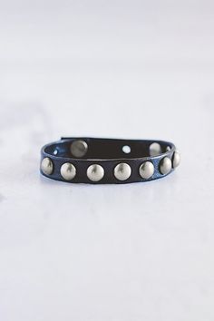 The Dotty stacker bracelet is handmade from lamb leather and features a row of brushed silver domed rivets. **Contents** * Lambskin leather, zinc alloy hardware * Button clasp closure * Handmade **Care/Import** * Made in the USA **Dimensions** * Adjustable to fit wrist sizes 6.5”-8” | Giving Bracelets Brushed Silver Dotty Leather Bracelet at Free People in Black Leather Accessories Handmade, Lambskin Leather, Leather Accessories, Womens Jewelry Bracelets, Free People, Leather Bracelet, Jewelry Accessories, Women Jewelry, Leather