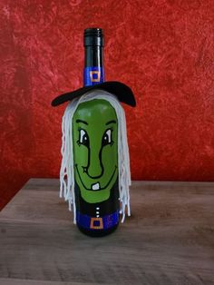 a bottle with a witch's face painted on it sitting on top of a wooden table