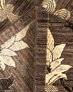 two brown and white rugs on top of each other, one with an image of leaves