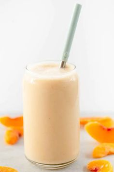 a smoothie in a glass with a straw and orange peels on the side