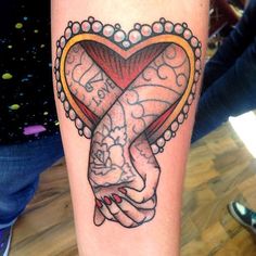 a woman's arm with a tattoo on it that has a heart and two hands holding each other