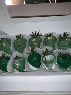 chocolate covered strawberries with green and gold decorations in a white box on top of a stove