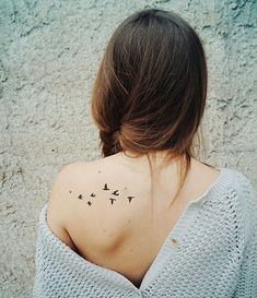 the back of a woman's shoulder with birds on her left shoulder and right arm