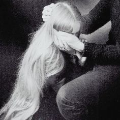 a black and white photo of a woman covering her face with her hands while sitting down