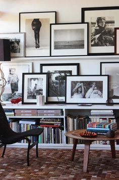 a living room filled with lots of books and pictures on the wall next to a coffee table