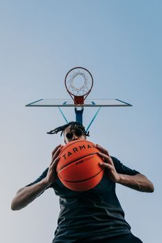 a man holding a basketball up to his face with the rim in front of him