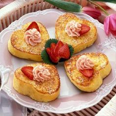 four heart shaped pastries on a plate with strawberries