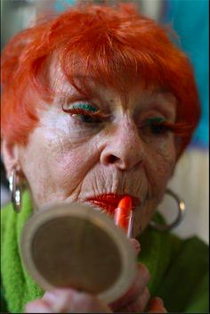 an older woman with red hair is brushing her teeth