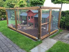 a chicken coop in the middle of a yard with grass around it and a red house on top