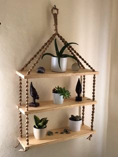 three wooden shelves with plants and rocks on them, hanging from the wall in front of a white wall