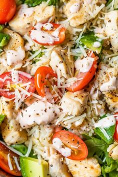 a salad with chicken, tomatoes, lettuce and cheese on it in a bowl