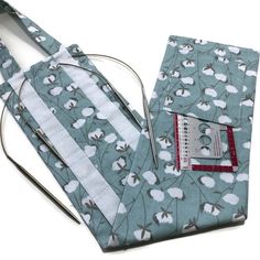 a pair of scissors sitting on top of a blue flowered fabric bag with white flowers