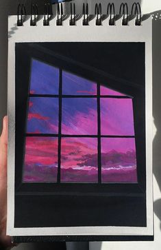 a person holding up a drawing of a window at sunset with the sky in the background