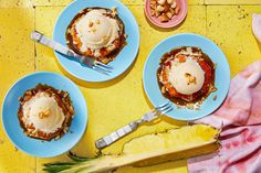 three blue plates topped with desserts next to a pineapple on a yellow table