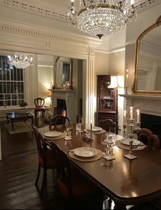 the dining room table is set with place settings for six people and has candles on it