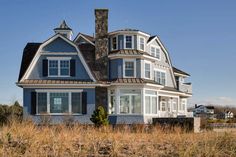 a large blue house sitting on top of a dry grass field