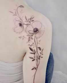 the back of a woman's shoulder with flowers and leaves on her left arm