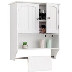 a white bathroom cabinet with towels hanging on the wall