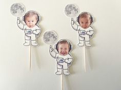 an astronaut cake topper with two babys on it and the moon in the background